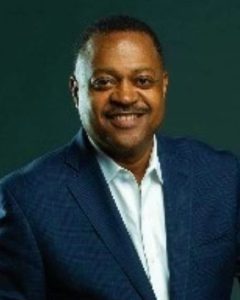 A man in a suit and tie smiling for the camera.