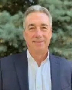 A man in a suit and tie standing next to a tree.